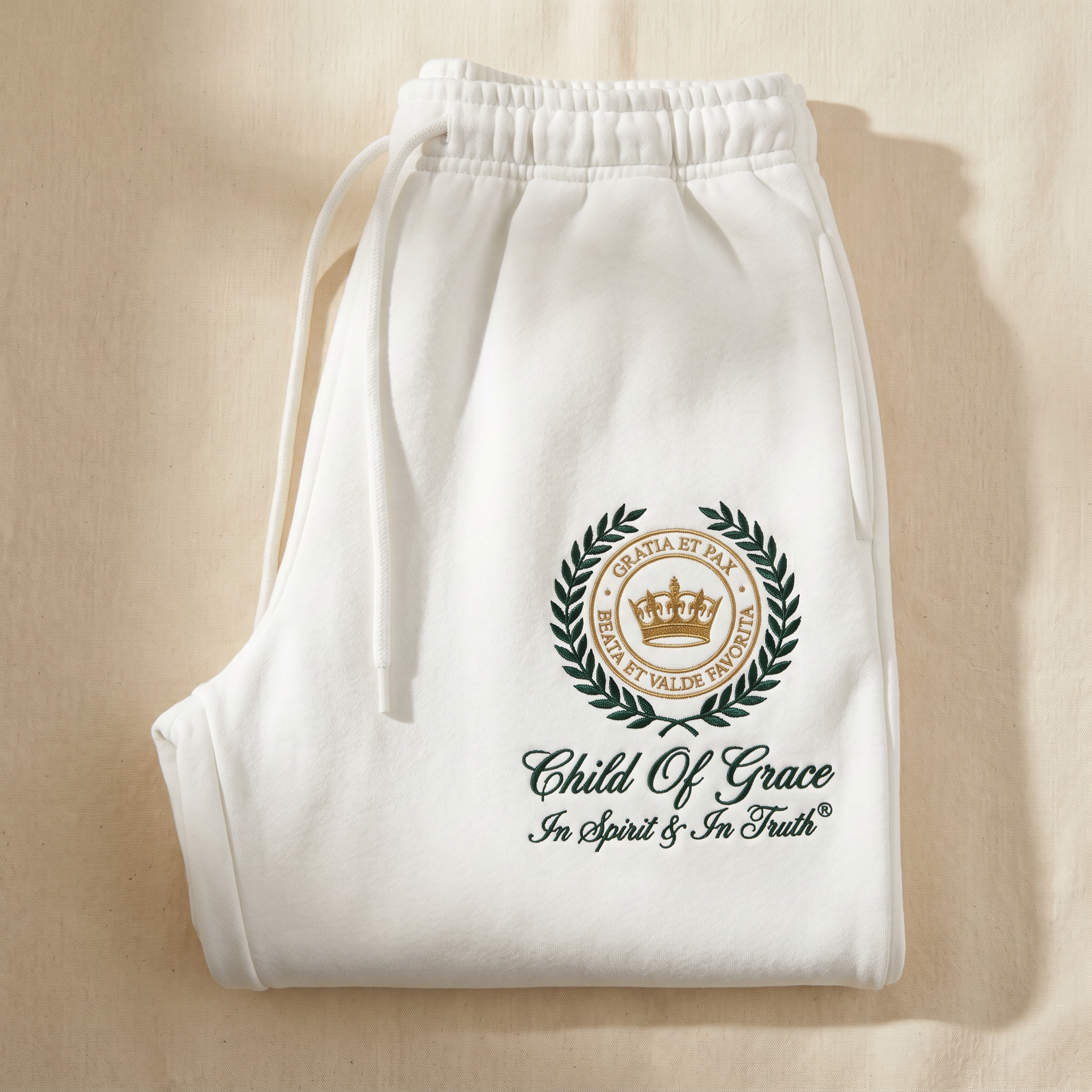 Genesis Crest Sweatpants — Cloud White with hunter green and antique gold embroidered crest, folded flat-lay
